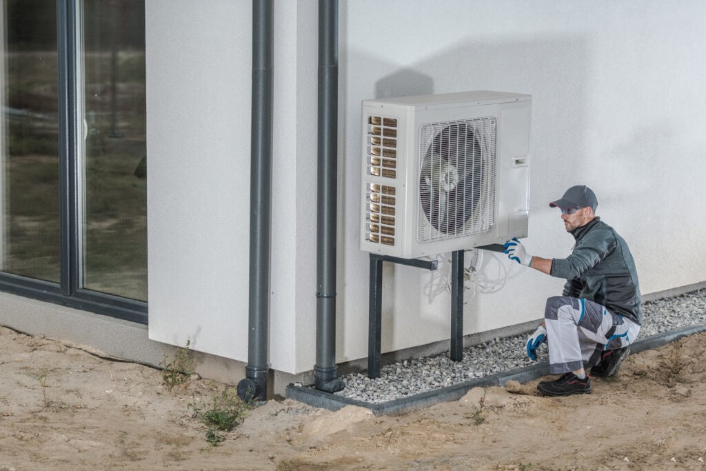 Un technicien finalise l'installation de l'unité extérieure d'une thermopompe murale. 