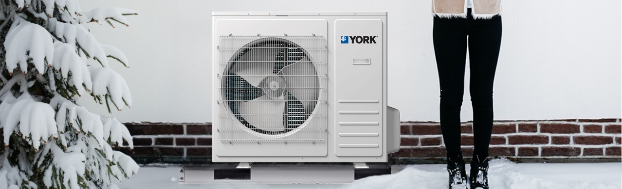 Femme posant à côté d'une thermopompe centrale York en hiver