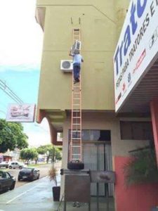 Installateurs en chauffage, ventilation et climatisation travaillant dangereusement dans une échelle