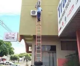 Installateurs en chauffage, ventilation et climatisation travaillant dangereusement dans une échelle