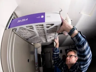 Un homme remplace le filtre à fournaise en respectant le sens du filtre