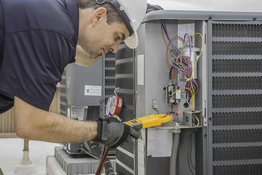 Technicien en chauffage, ventilation et climatisation effectuant un test d'ampérage d'une thermopompe centrale