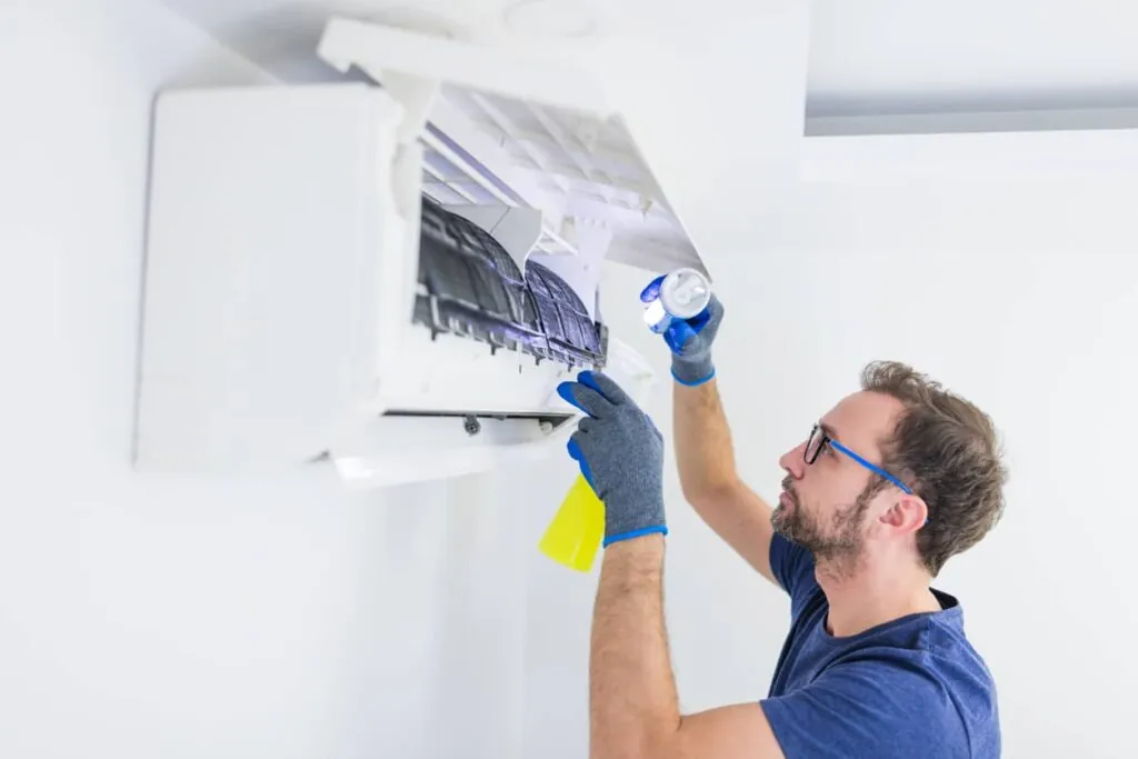 Un expert qui est en train de faire le nettoyage d’un climatiseur mural