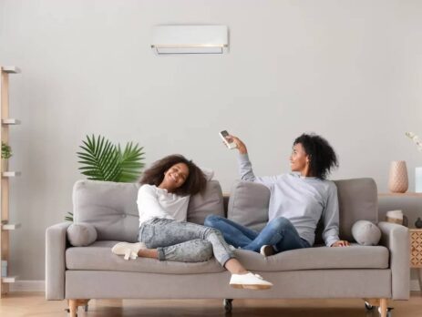 A mother and daughter relaxing on the sofa under the air conditioning of the heat pump.