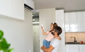 Un père et sa fille activent le climatiseur mural dans la cuisine