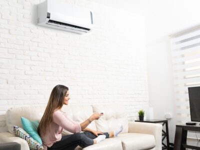 Woman watching TV while enjoying the cool air from the wall-mounted air conditioner she just bought.