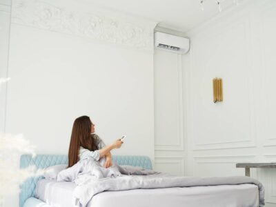 Jeune femme assise sur son lit qui démarre son air climatisé.