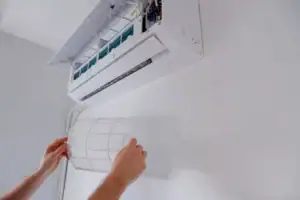 Woman repositioning the filter on her wall-mounted heat pump