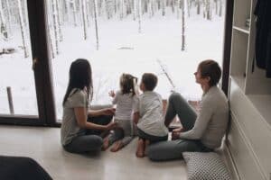A family looks at the winter landscape through the window.