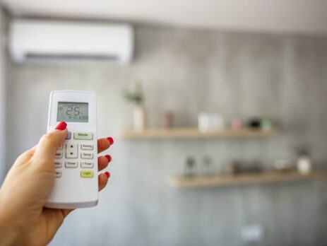 Femme ajustant les réglages de sa thermopompe à l’aide de la télécommande.